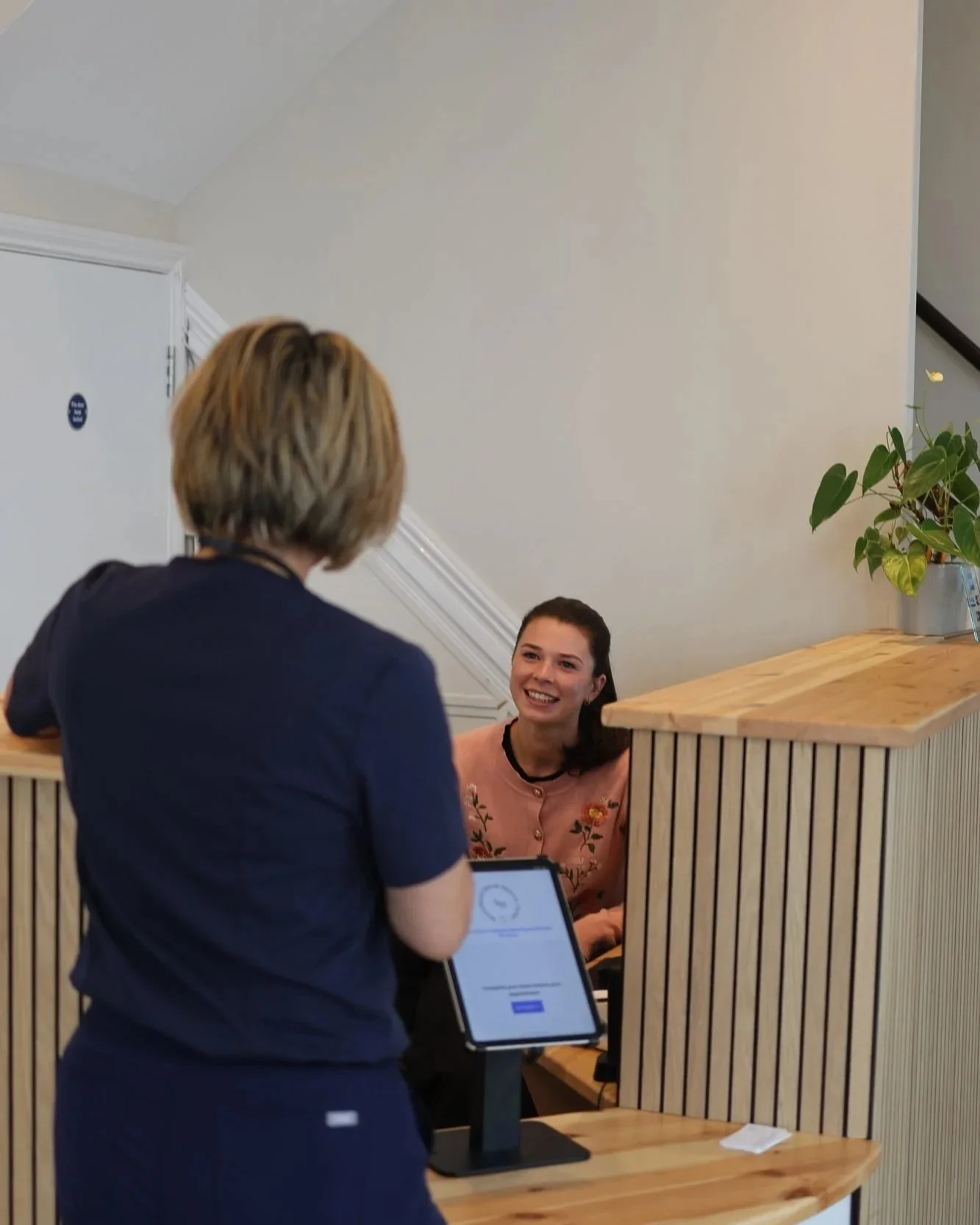 The welcome desk at Sedgemead House, with a patient being greeted at reception.